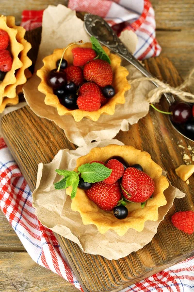 Tasty tartlets with berries on wooden table — Stock Photo, Image