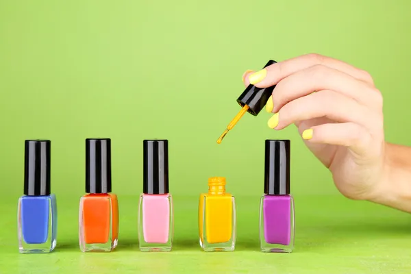 Female hand with stylish colorful nails holding bottle with nail polish — Stock Photo, Image