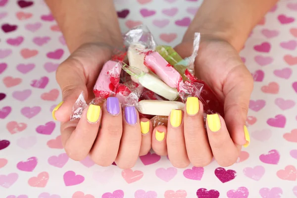 Női kézi és elegáns színes körmök holding színes cukorkák — Stock Fotó