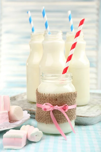 Melk in flessen met papier rietjes — Stockfoto