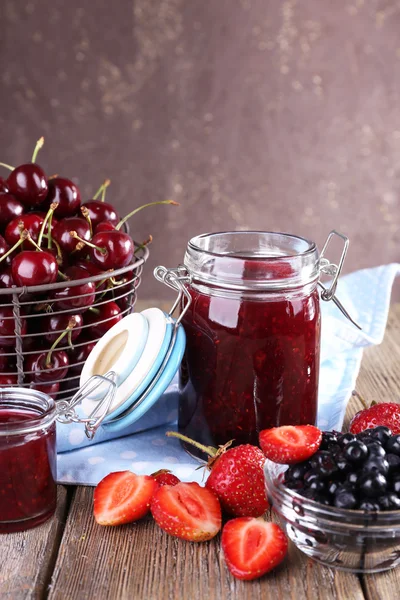 Jam in glazen pot op tafel, bessen close-up — Stockfoto