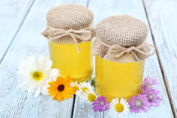 Džbán plný lahodné čerstvé medu a kytice na dřevěný stůl — Stock fotografie