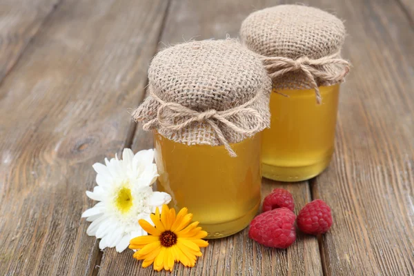 Glas voll leckerem frischen Honig und Wildblumen auf Holztisch — Stockfoto