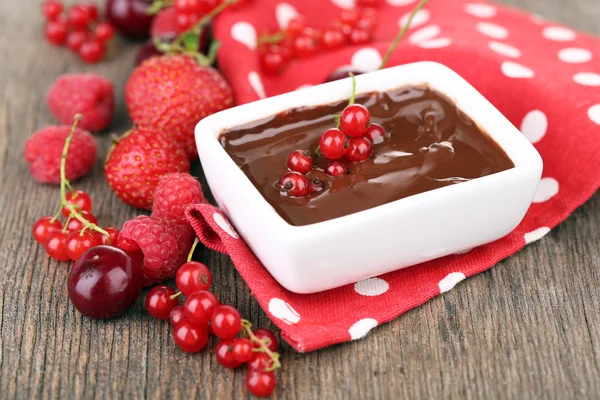 Maturare bacche dolci e cioccolato liquido sul tavolo di legno — Foto Stock