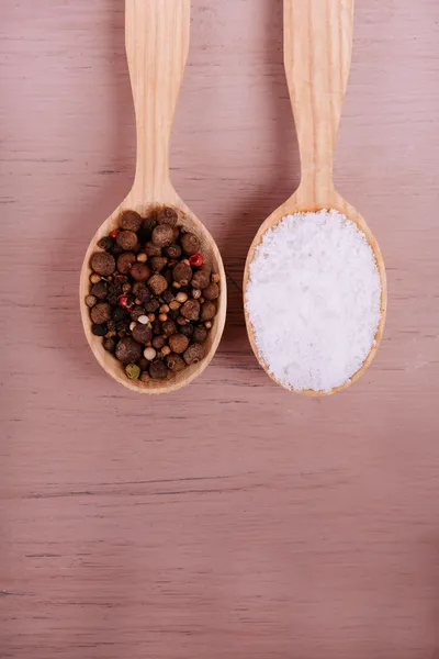 Salt och peppar i sked på träbord närbild — Stockfoto