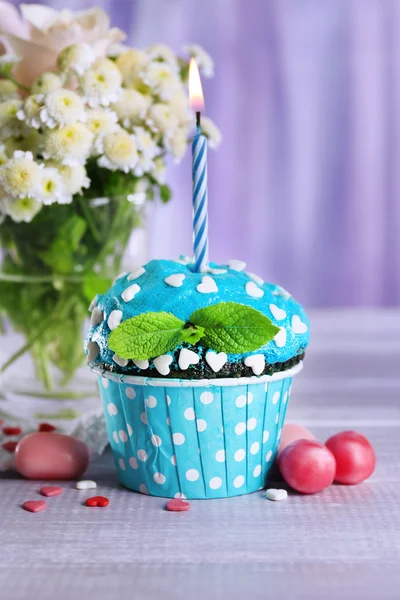 Tasty cupcake on table, on fabric background — Stock Photo, Image