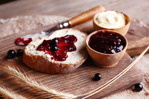 Fresh toast with homemade butter and blackcurrant jam on wooden background
