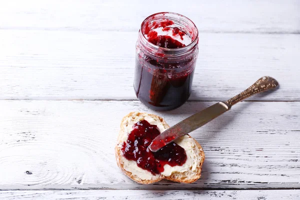 Fresh bread with homemade butter and blackcurrant jam on light wooden background — Stock Photo, Image