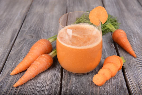 Vaso de jugo de zanahoria y zanahorias frescas sobre fondo de madera —  Fotos de Stock