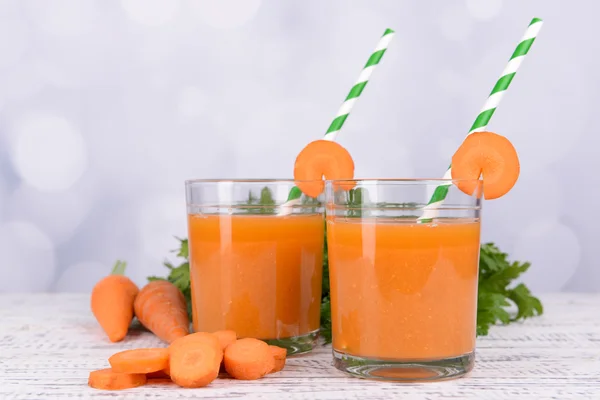 Gläser Karottensaft mit frischen Möhren und Petersilie auf dem Tisch vor hellem Hintergrund — Stockfoto