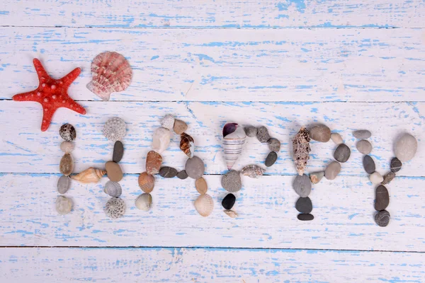 Wort glücklich aus Muscheln und Steinen auf Holzgrund — Stockfoto