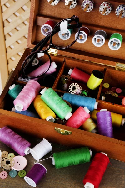 Colorful threads for needlework in wooden box on shelf in room — Stock Photo, Image
