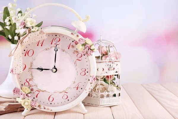 Beautiful vintage alarm clock with flowers on light background — Stock Photo, Image
