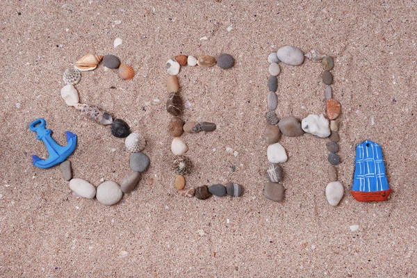 Wort Meer aus Muscheln und Steinen auf Sand — Stockfoto