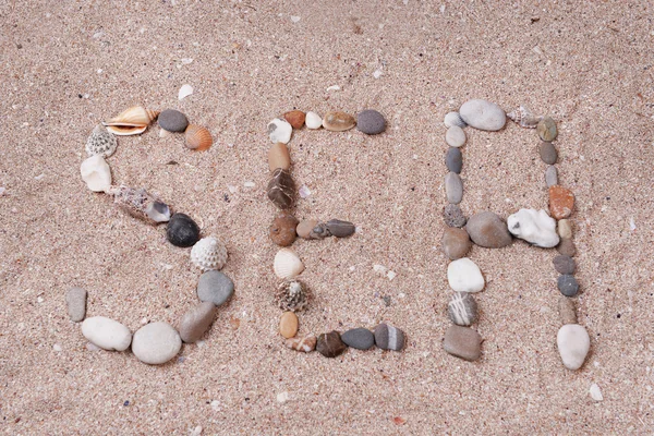 Wort Meer aus Muscheln und Steinen auf Sand — Stockfoto