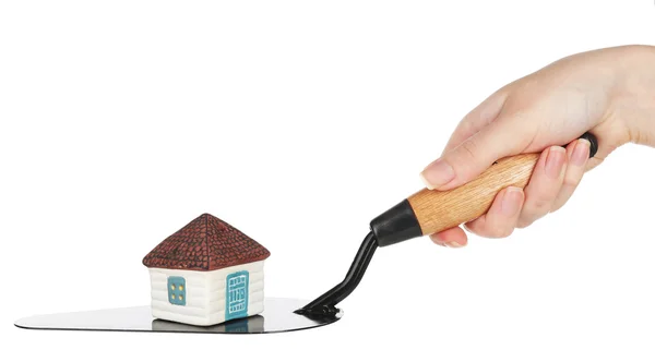 Hand holding wooden toy house on trowel — Stock Photo, Image