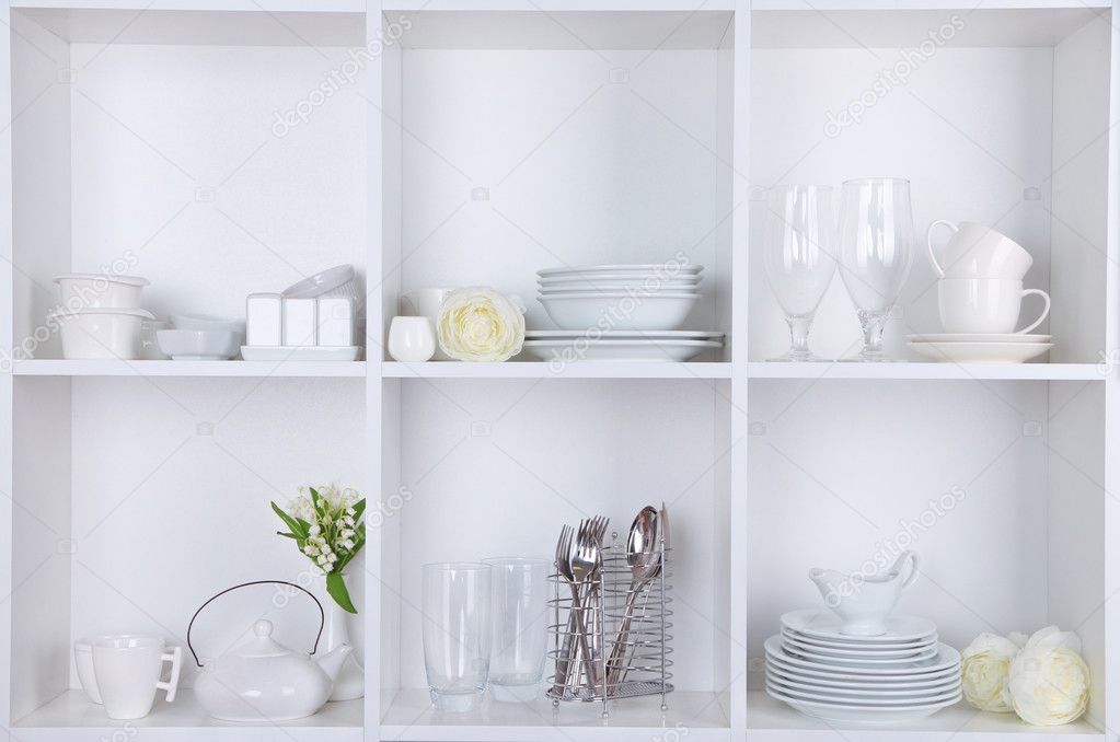Different white clean dishes on wooden shelves