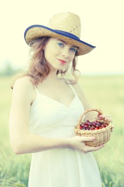 Woman holding basket with cherries in field clipart