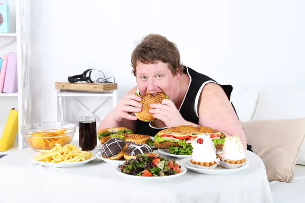 Grasso uomo mangiare un sacco di cibo malsano — Foto Stock