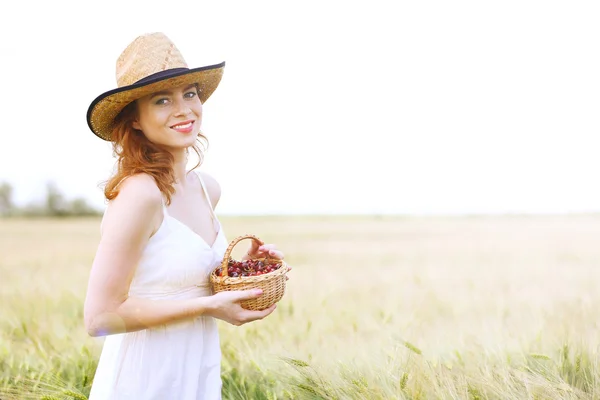 Frau hält Korb mit Kirschen im Feld — Stockfoto
