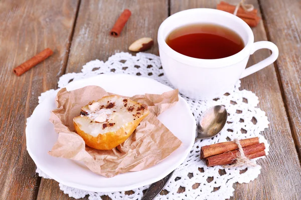 Poires cuites au four avec sirop sur une assiette et une tasse de thé — Photo