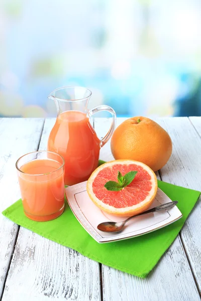 Половина грейпфрута, стеклянный кувшин со свежим соком — стоковое фото