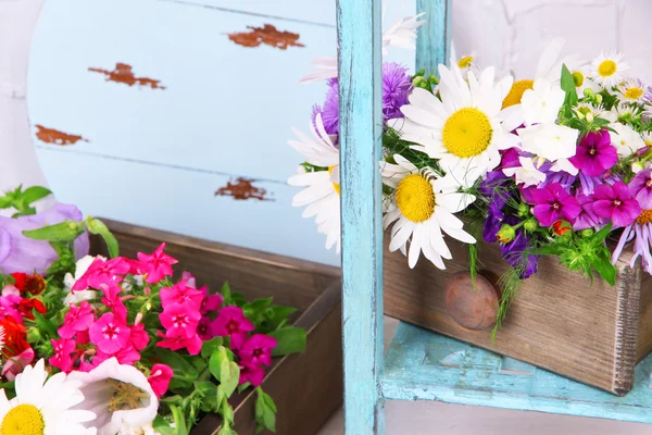 Beautiful flowers in crates on wooden stand — Stock Photo, Image
