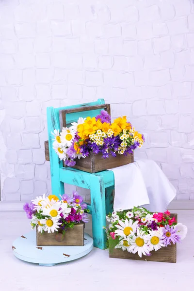 Красивые цветы в ящиках на маленьком кресле — стоковое фото