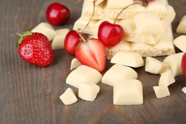 White broken chocolate bar and fresh berries, on color wooden background — Stock Photo, Image
