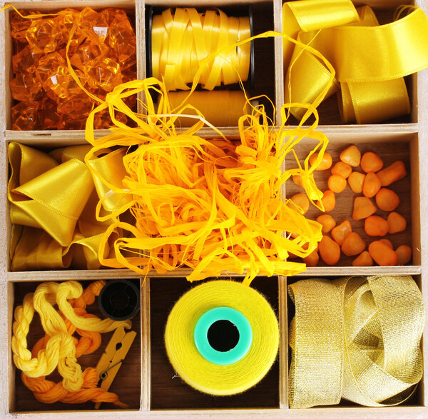 Yellow thread and material for handicrafts in box isolated on white