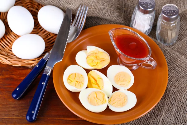Boiled eggs on plate on wooden board on tablecloth on wooden table — Stock Photo, Image