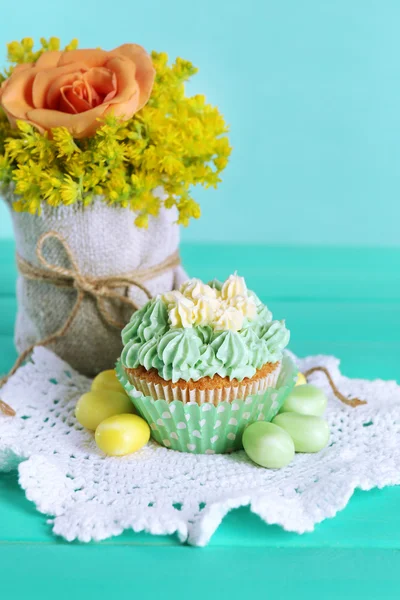 Tasty cupcake on table, on turquoise background — Stock Photo, Image