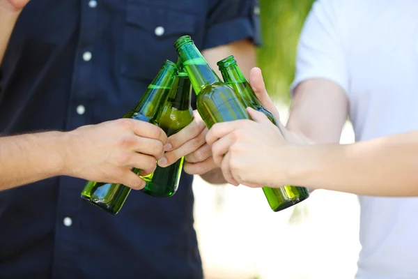 Hands holding beer bottles close up