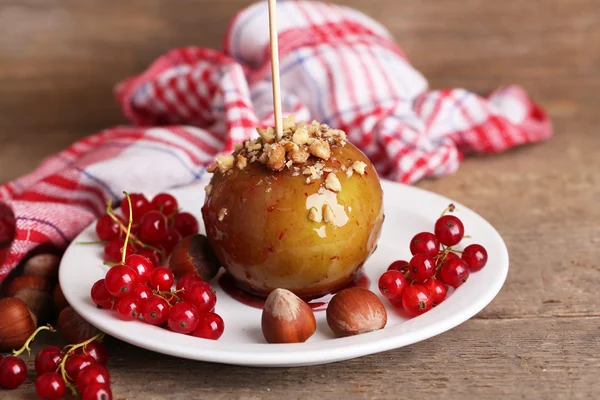 Sweet caramel apple on stick with berries — Stock Photo, Image