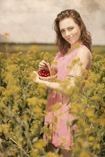 Hermosa joven mujer sosteniendo canasta de mimbre con cerezas en el campo — Foto de Stock