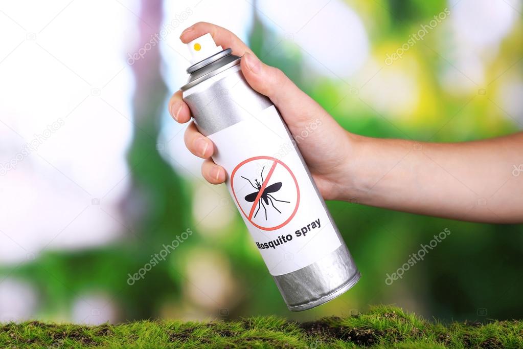 Hand holding mosquito spray on nature background