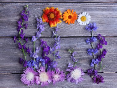 Wildflowers on wooden background clipart