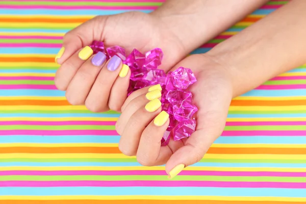 Mão feminina com unhas coloridas segurando pedras decorativas — Fotografia de Stock