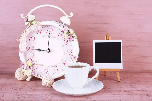 Vintage alarm clock with flowers and cup of tea — Stock Photo, Image