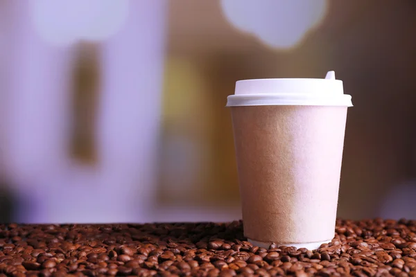 Cup of strong coffee on coffee beans, on bright background — Stock Photo, Image