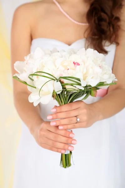 Bride holding wedding bouquet of white peonies, close-up, on light background — Stock Photo, Image