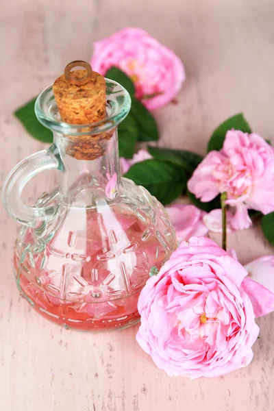 Rose oil in bottle on color wooden background — Stock Photo, Image