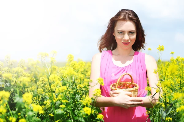 Belle jeune femme tenant panier en osier avec des cerises dans le champ — Photo