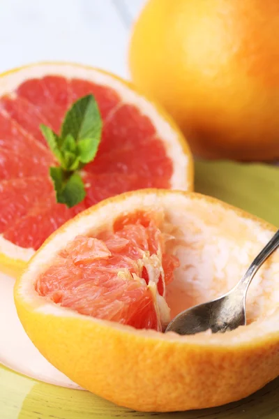 Ripe grapefruits on plate, on color wooden background — Stock Photo, Image