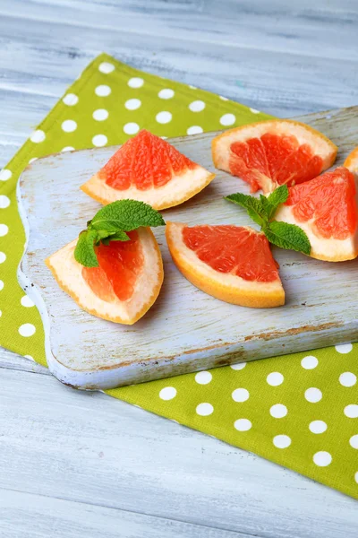 Rijp grapefruits op snijplank, op houten tafel, op lichte achtergrond — Stockfoto