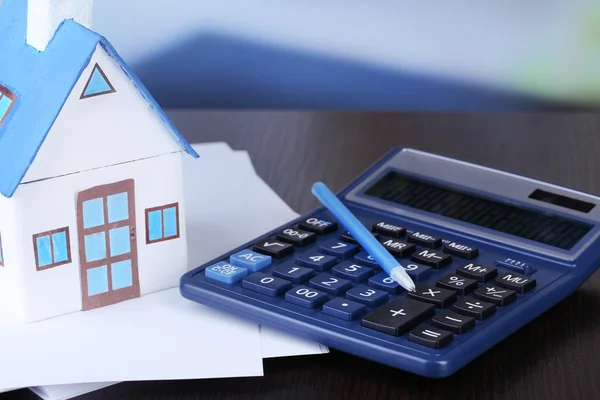 Casa de juguete y calculadora en primer plano de la mesa — Foto de Stock