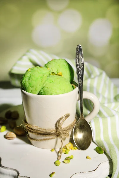 Sabroso helado de pistacho en taza sobre mesa de madera, sobre fondo claro — Foto de Stock