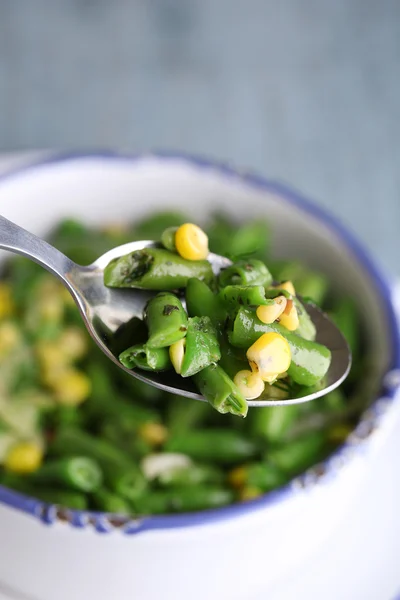 Salat mit grünen Bohnen und Mais, in Schüssel, auf farbigem Holzgrund — Stockfoto