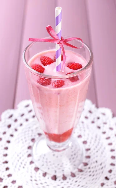 Glass of raspberry smoothie drink on wooden background