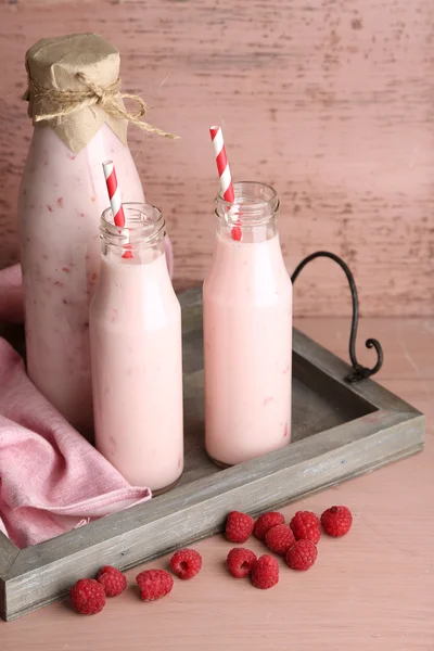 瓶的粉红色的木制背景上可口的覆盆子果汁饮料 — 图库照片